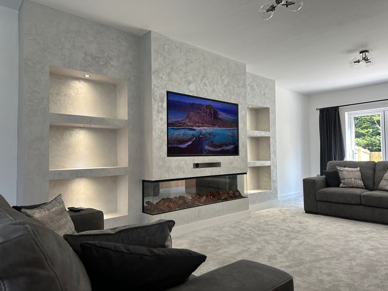 Bespoke slat media wall with fire-effect TV and built-in shelving by RV Media Walls