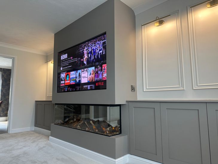 Bespoke sage-green media wall with built-in alcoves and electric fireplace by RV Media Walls